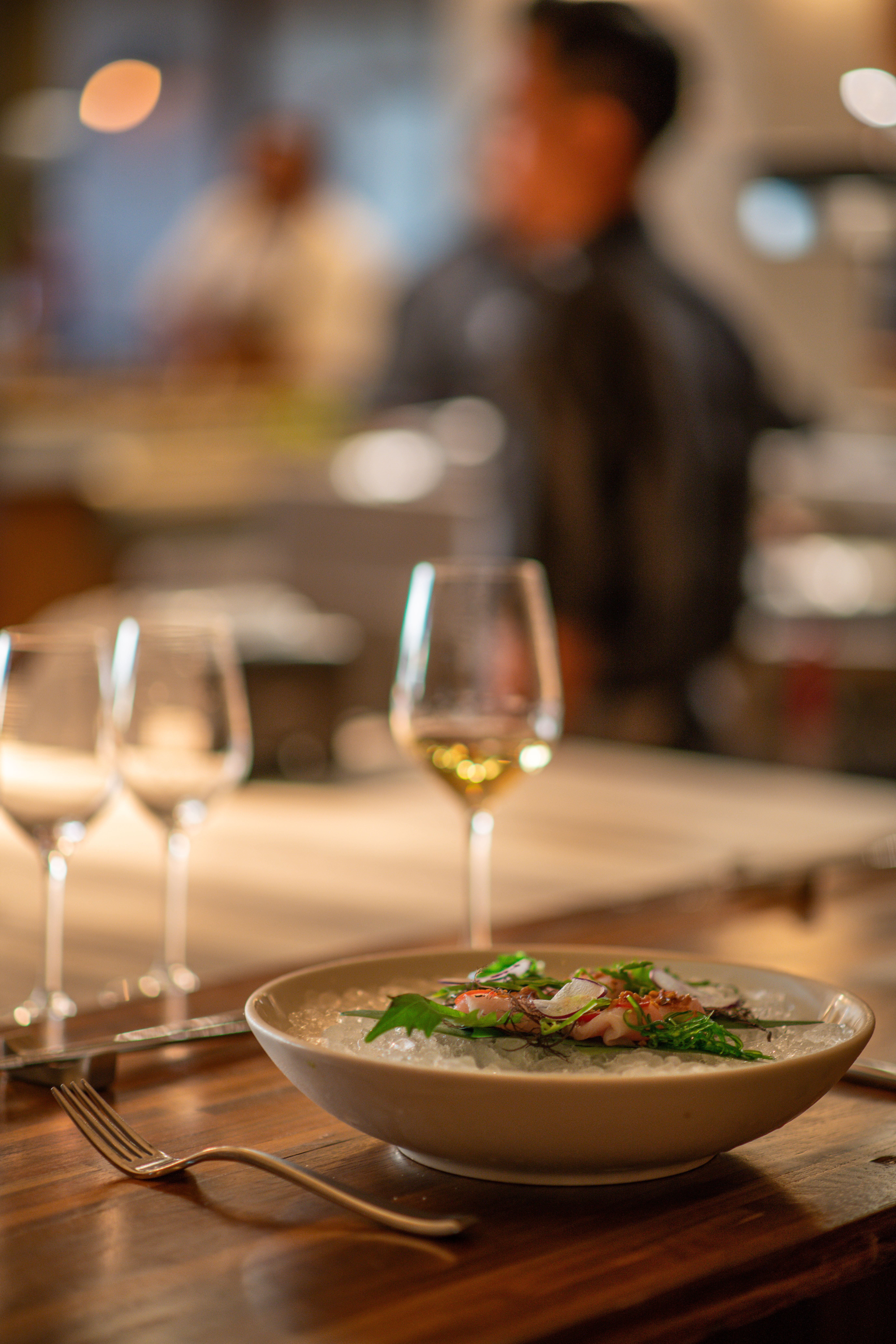 a bowl of food and glasses of wine on a table